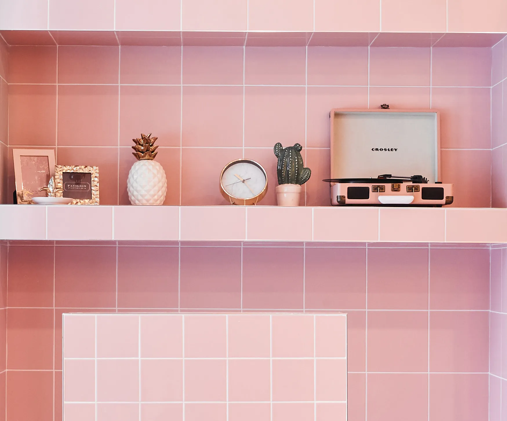 Interior Design - A pink tiled shelf displaying a record player, clock, cactus, and decorative items. Dexign Matter Studio