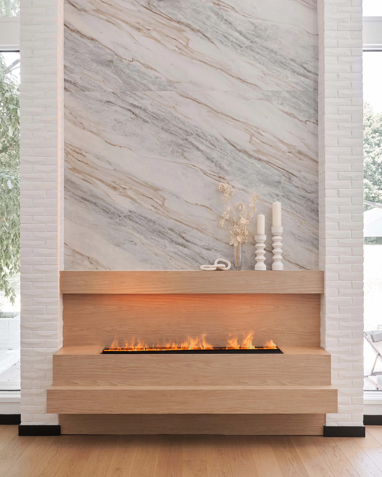 Interior Design - A modern fireplace with a wooden base and a marble wall featuring a natural stone pattern. Dexign Matter Studio