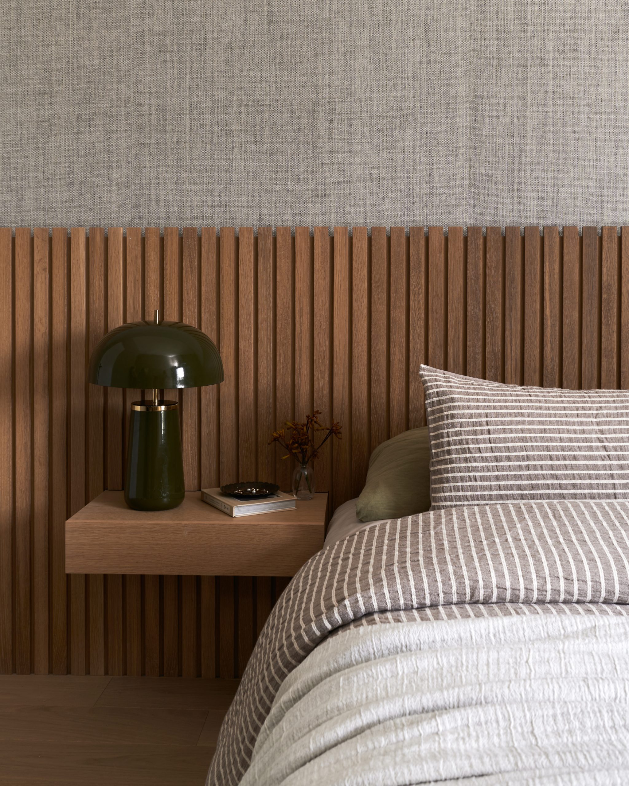 Interior Design - A modern master bedroom featuring a wooden accent wall and a green lamp on a bedside table. Dexign Matter Studio