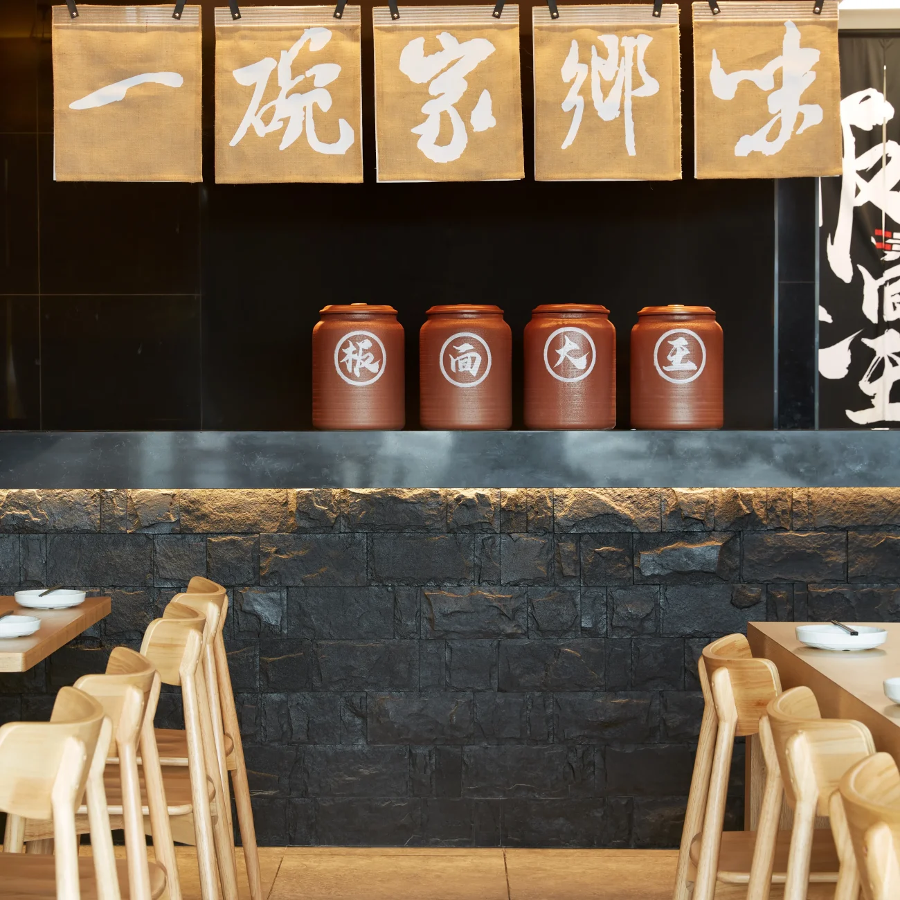 Interior Design - Interior view of a restaurant featuring wooden chairs and decorative jars on a shelf. Dexign Matter Studio