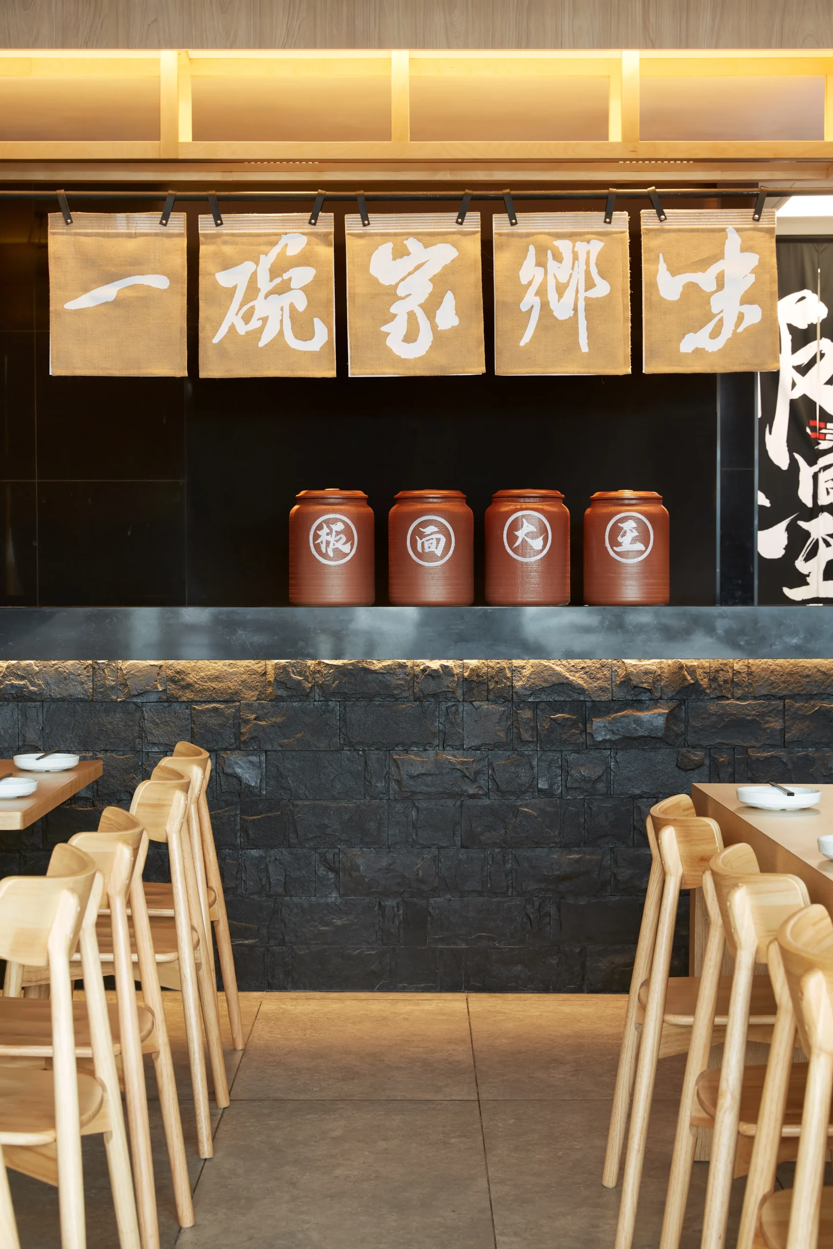 Interior Design - Interior view of a restaurant featuring wooden chairs and decorative jars on a shelf. Dexign Matter Studio