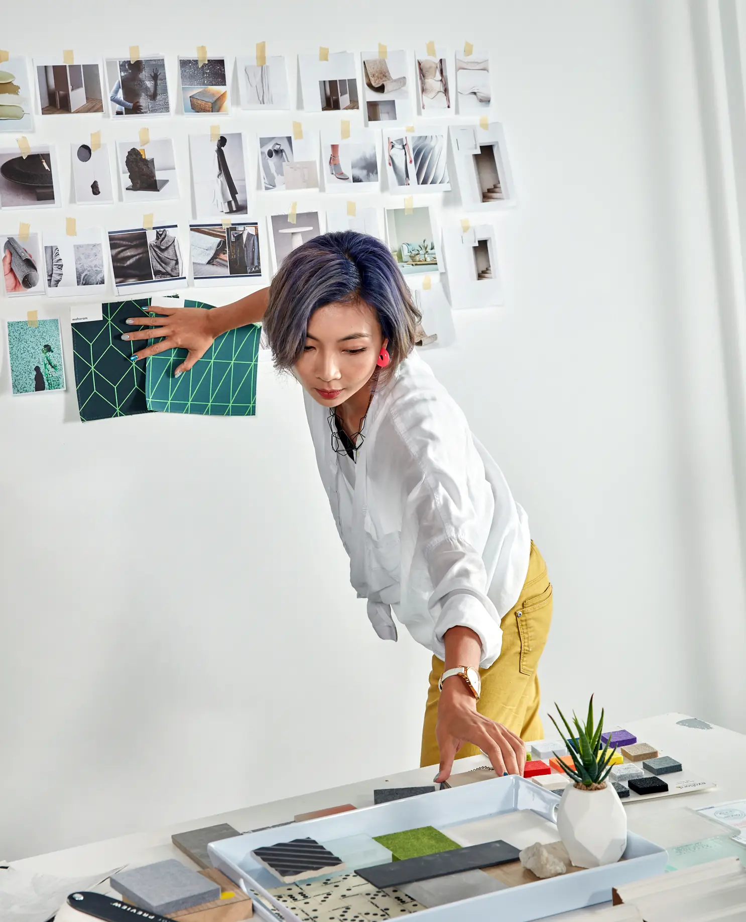 Interior Design - Interior designer arranging materials and images on a mood board in a studio setting. Dexign Matter Studio