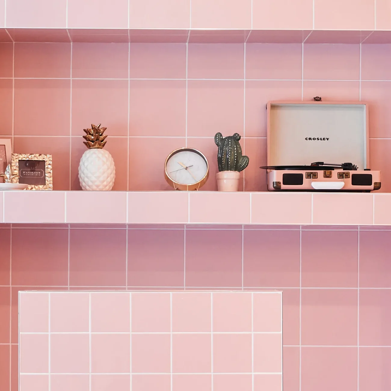 Interior Design - A pink tiled shelf displaying a record player, clock, cactus, and decorative items. Dexign Matter Studio