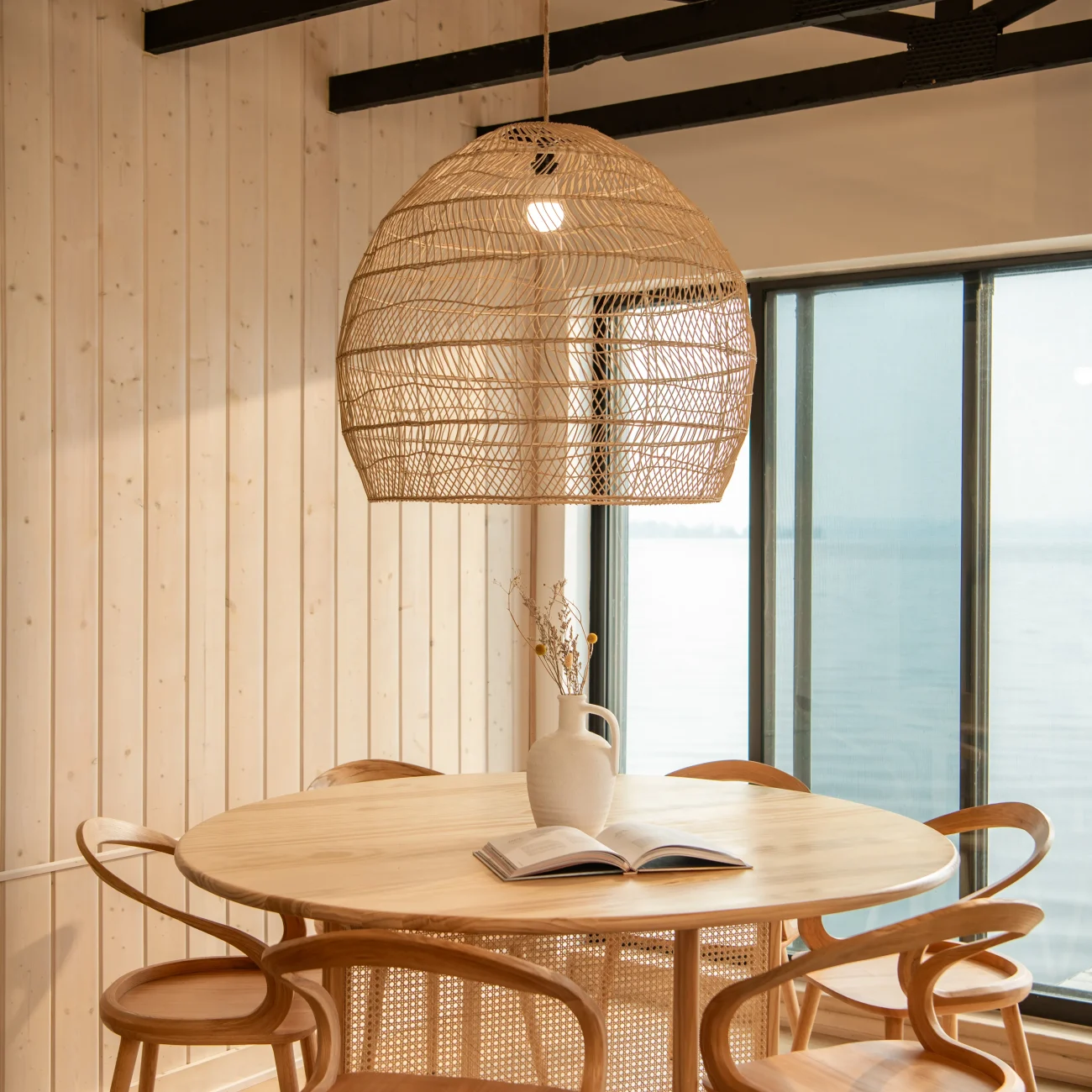Interior Design - Round wooden dining table surrounded by rattan chairs under a woven pendant light. Dexign Matter Studio
