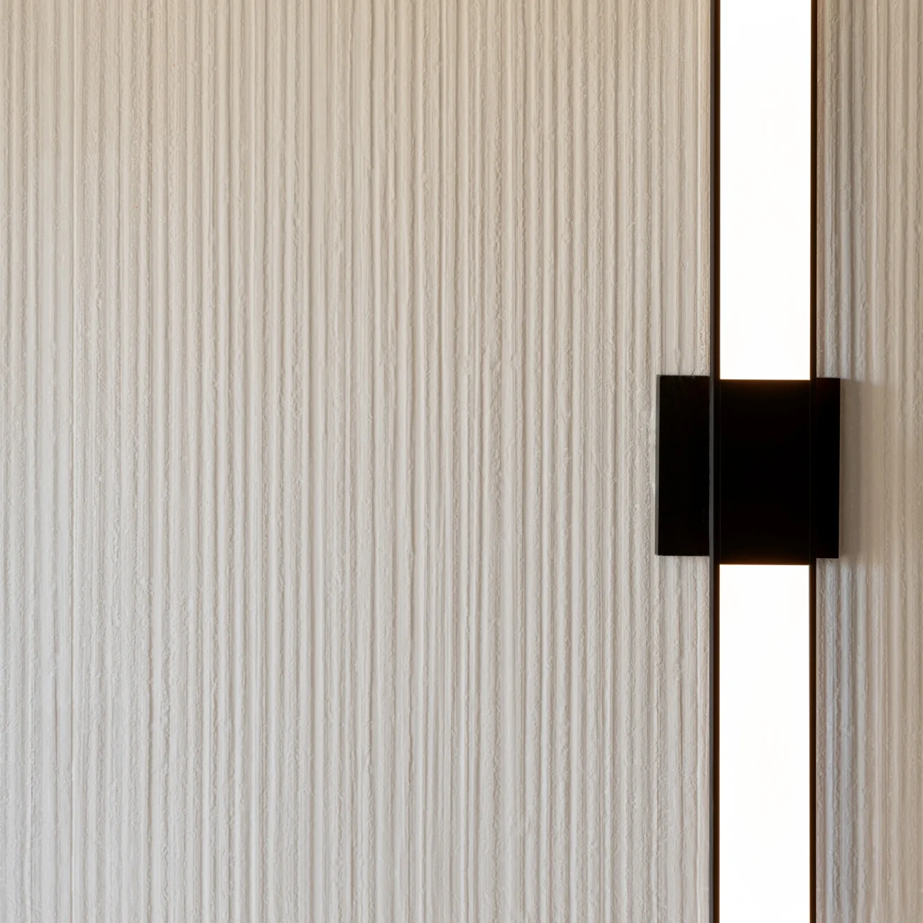 Interior Design - A modern wall sconce with a vertical light fixture mounted on a textured wall. Dexign Matter Studio