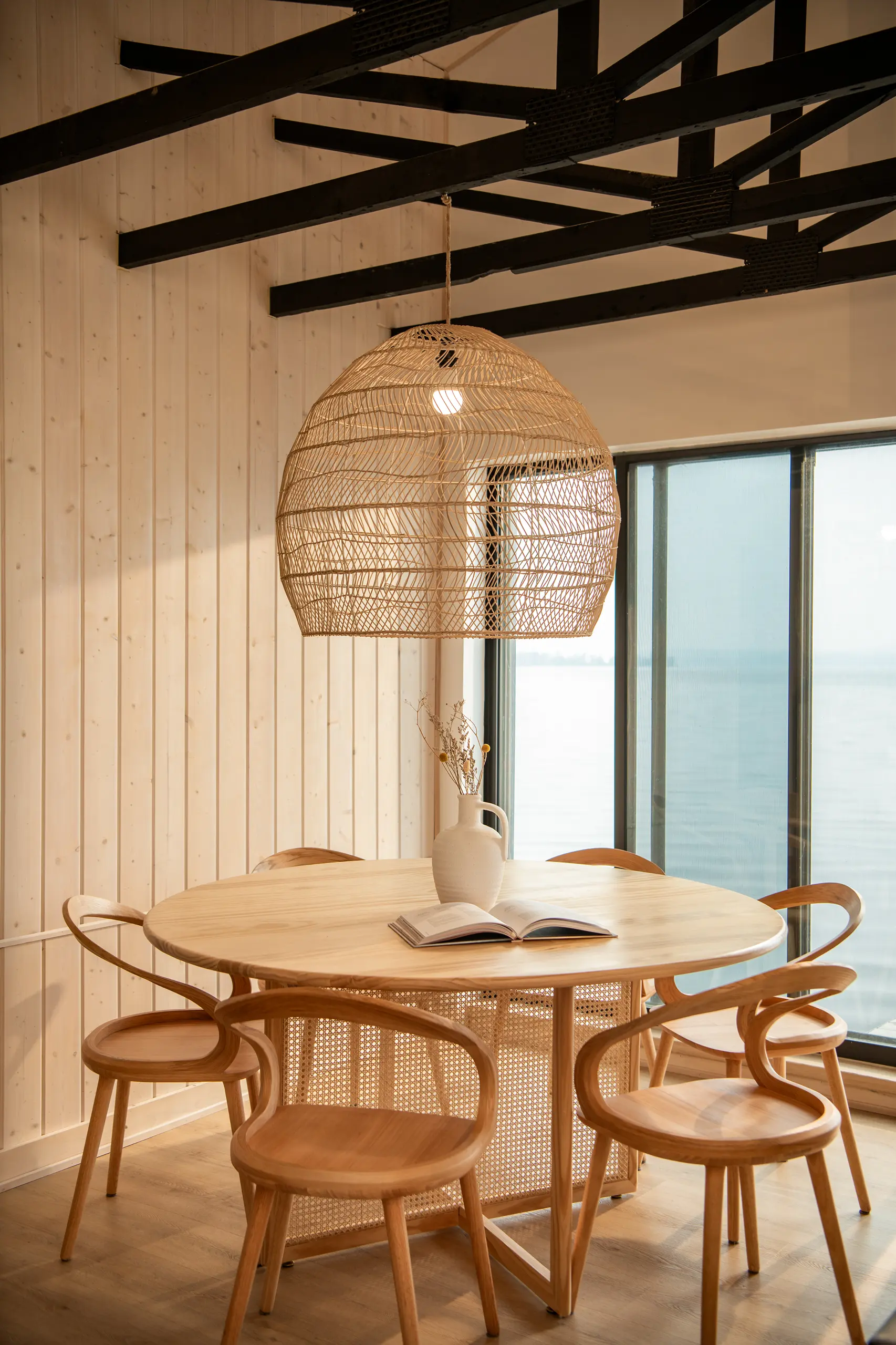 Interior Design - Round wooden dining table surrounded by rattan chairs with a large woven pendant light above. Dexign Matter Studio