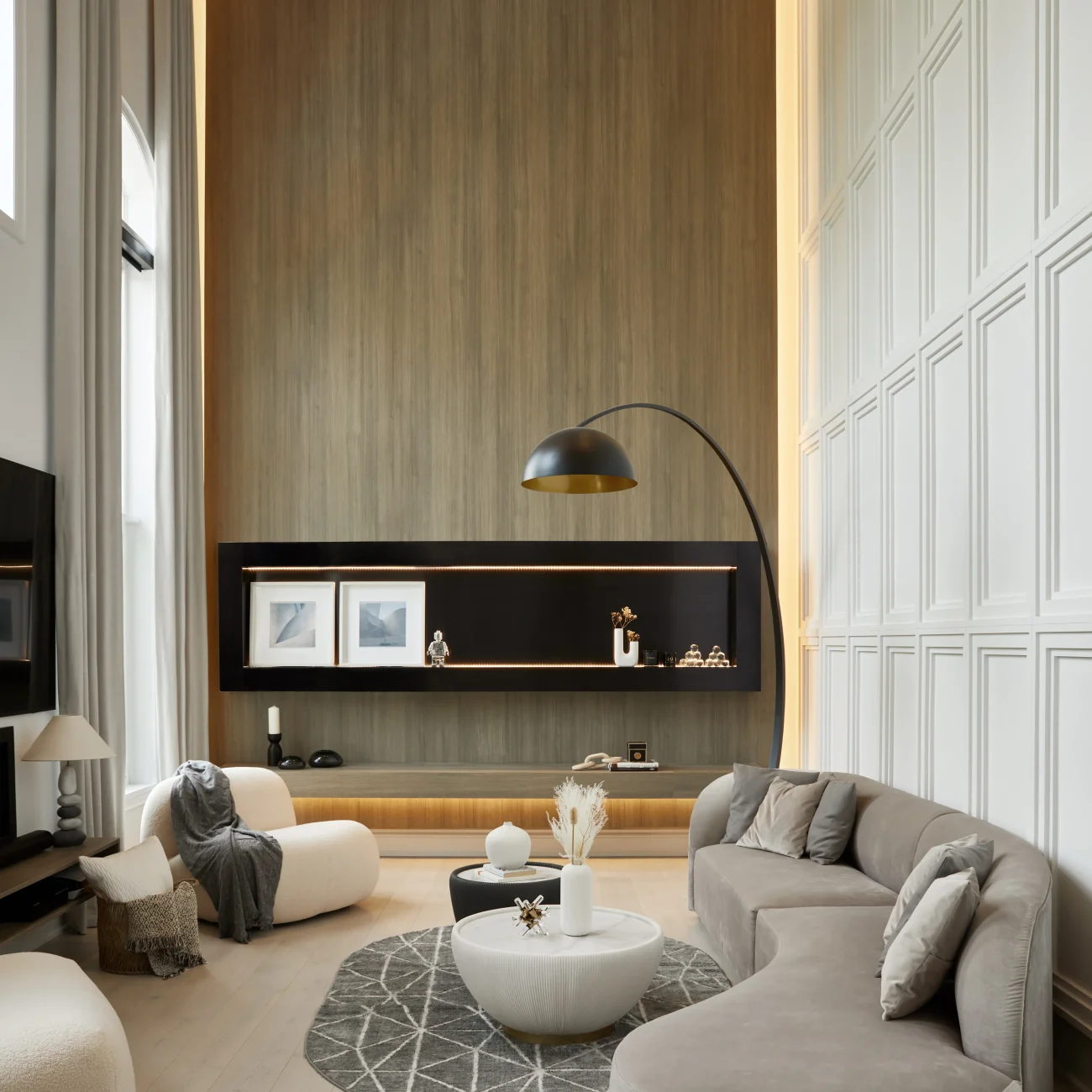 Interior Design - Contemporary living room featuring a curved sofa, coffee table, and decorative elements on a shelf. Dexign Matter Studio