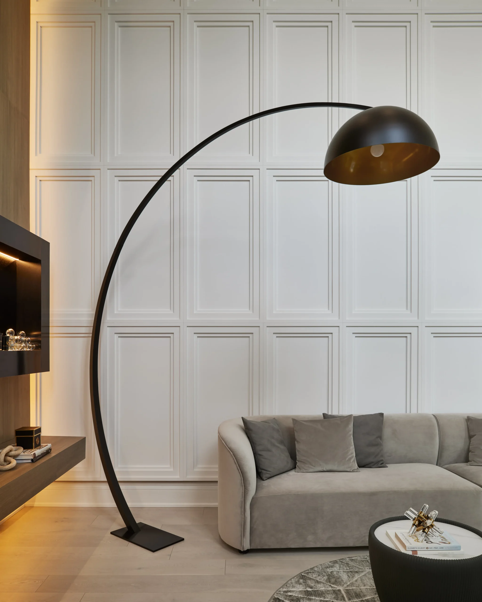 Interior Design - Arc floor lamp with a black shade positioned next to a light gray sofa in a modern interior setting. Dexign Matter Studio