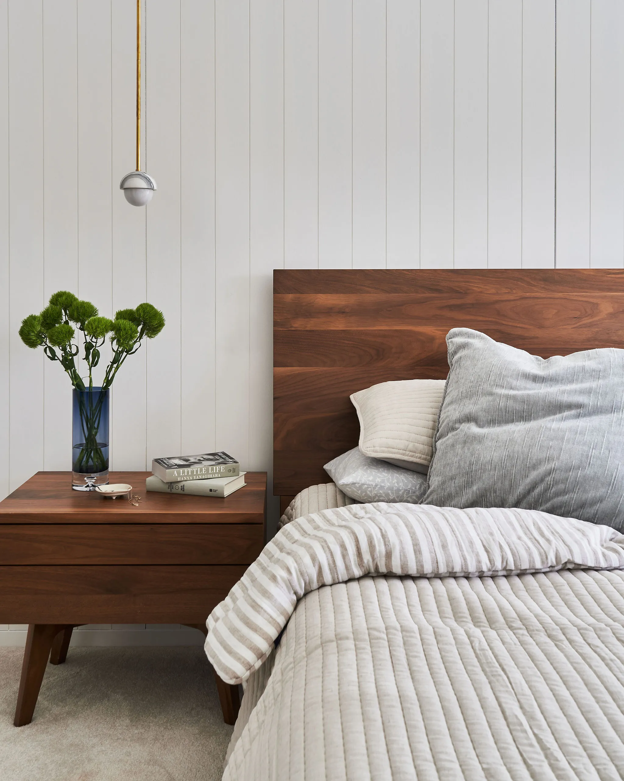 Interior Design - A modern bedroom featuring a wooden bed frame, nightstand, and decorative elements. Dexign Matter Studio