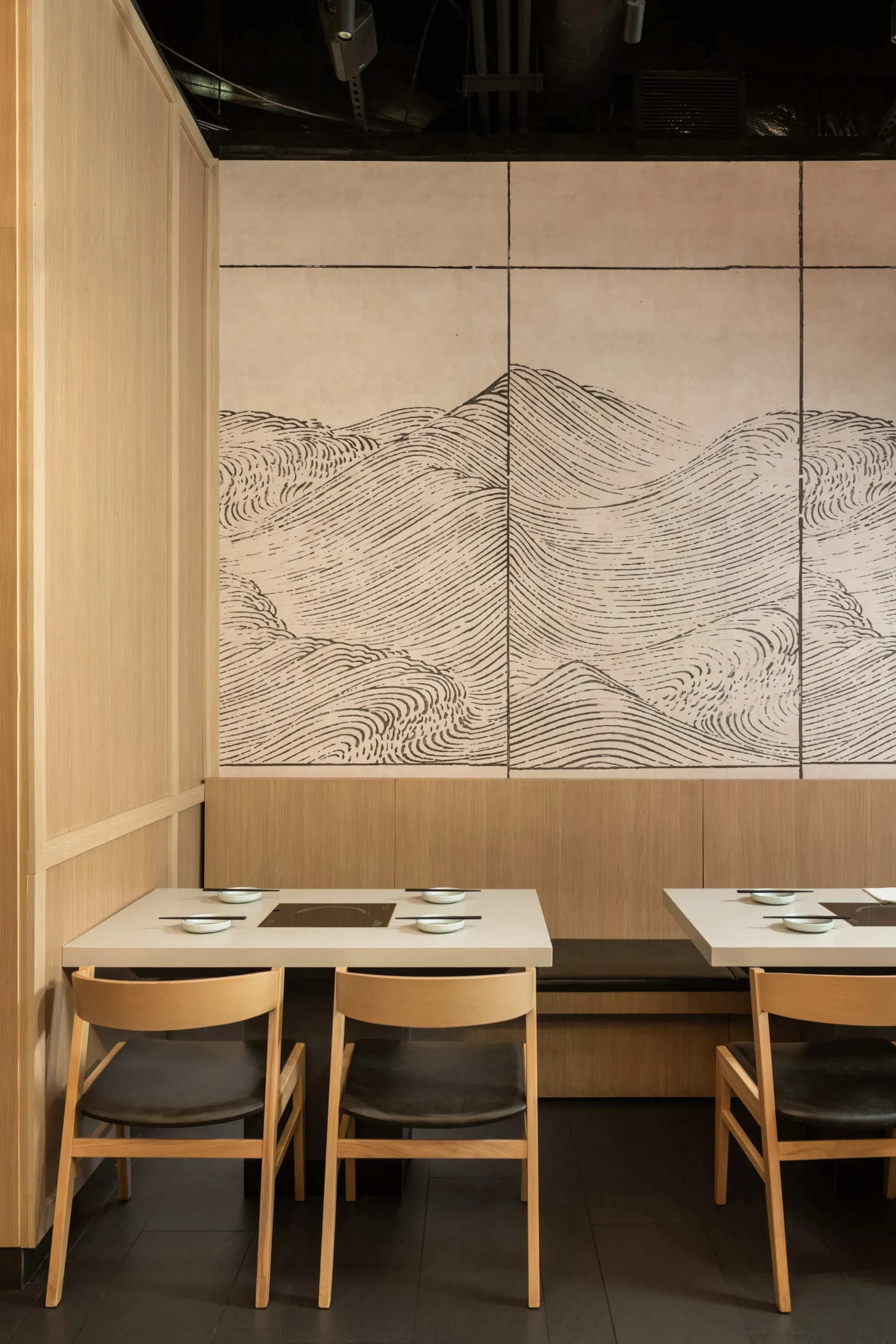 Interior Design - Interior view of a restaurant featuring wooden walls and a large mural of abstract mountain lines. Dexign Matter Studio
