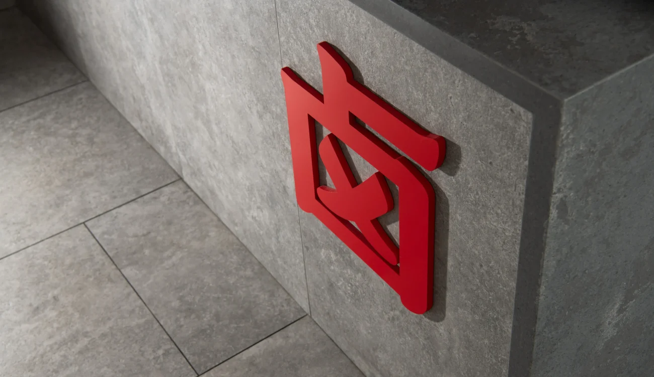 Interior Design - Red logo affixed to a gray stone wall in a modern interior setting. Dexign Matter Studio