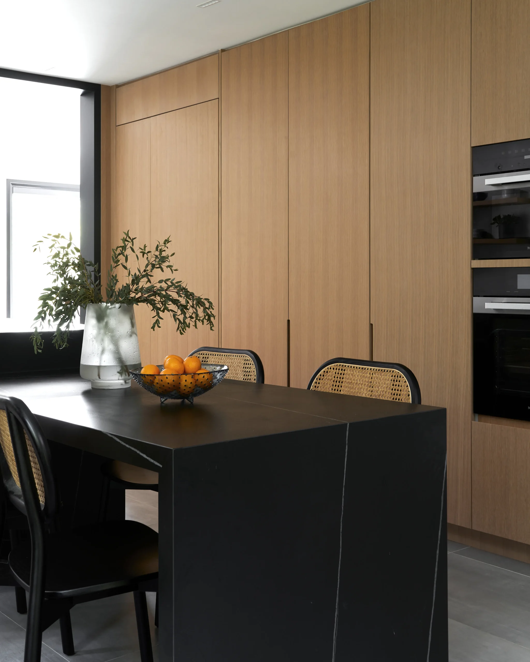 Interior Design - A modern kitchen counter featuring a black surface and a bowl of oranges. Dexign Matter Studio